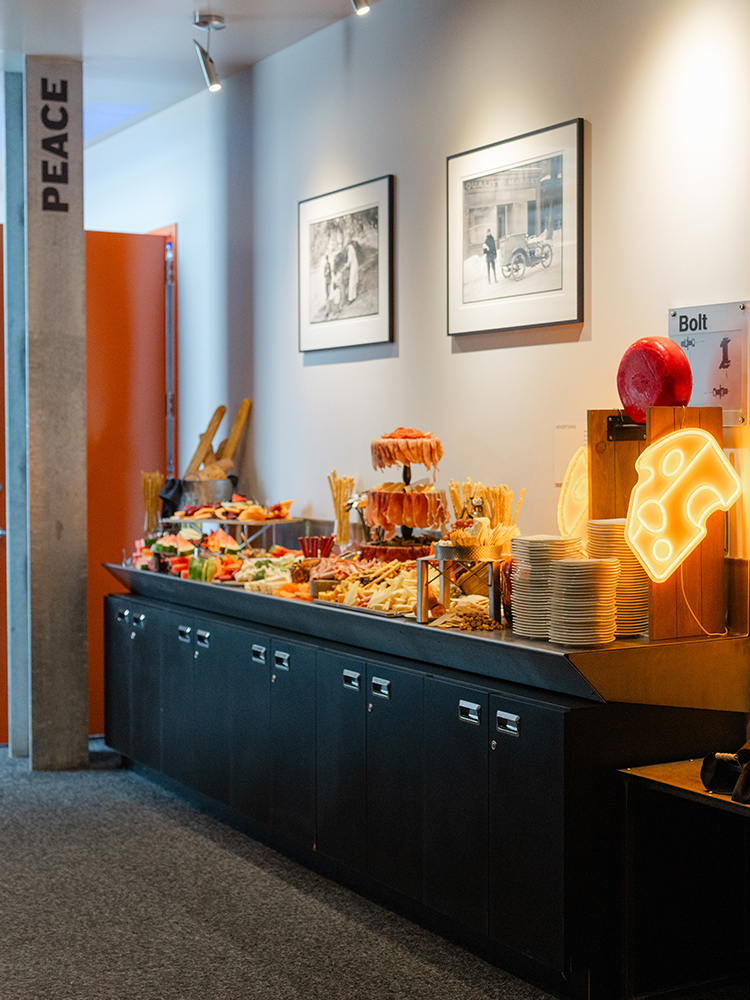 Snack buffet with chips, plates, and neon cheese sign on table
