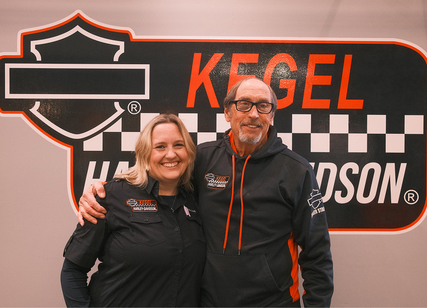 Katrina Kegel-Mather and Mark Kegel stand side by side in front of a Kegel Harley-Davidson sign