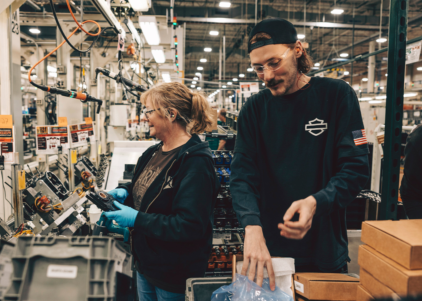 Dois trabalhadores montam componentes de motocicletas no chão da fábrica