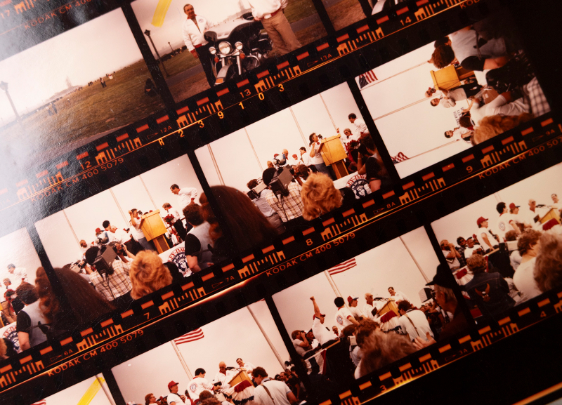 Strips of photographic film showing repeated images of people gathered at an outdoor event