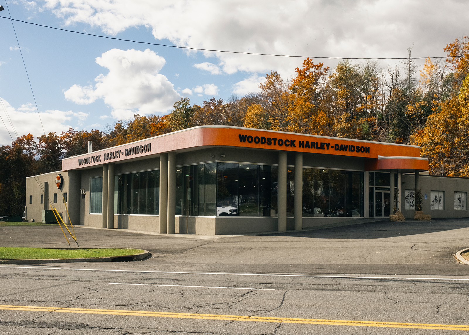 The exterior of Woodstock Harley-Davidson with fall foliage and blue skies.