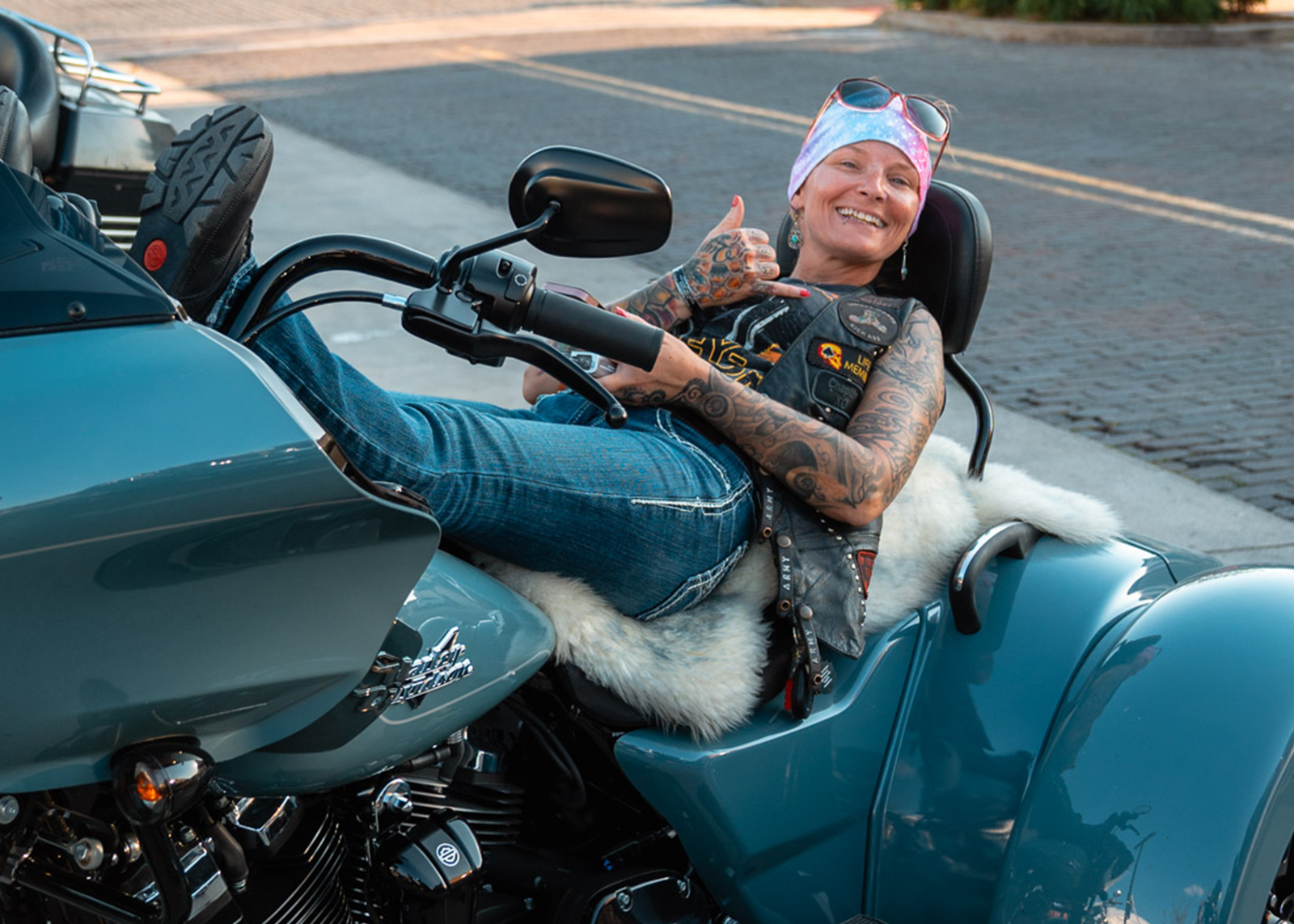 A woman kicks back on her trike and holds up the shoka sign with her hand 