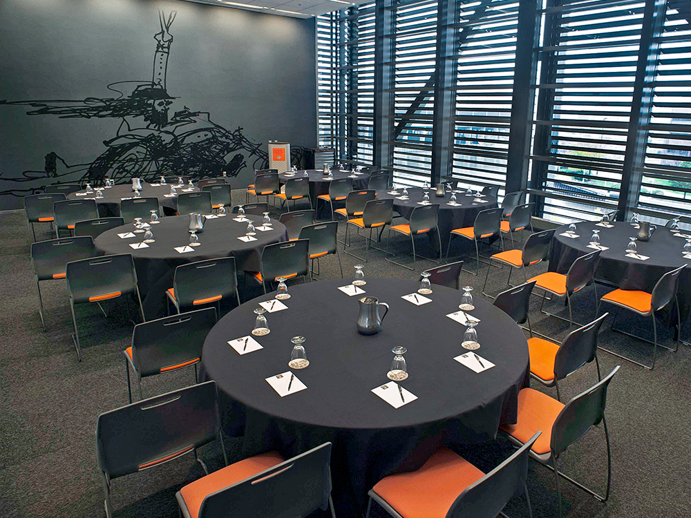 Round table setup with black linens and orange chairs in meeting room