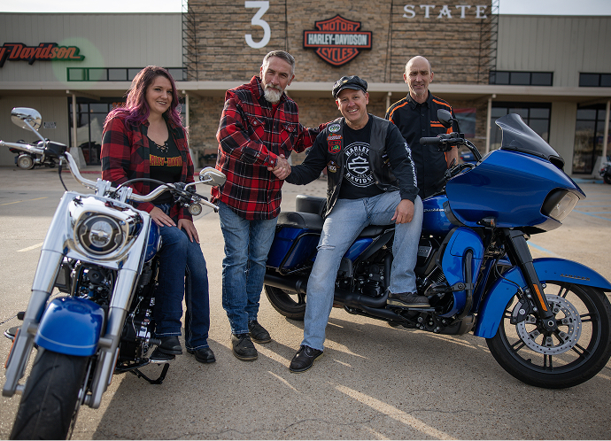 Platinum Tier winner Doug Sawyer sits with his new 2025 Fat Boy surrounded by staff at 3 State Harley-Davidson
