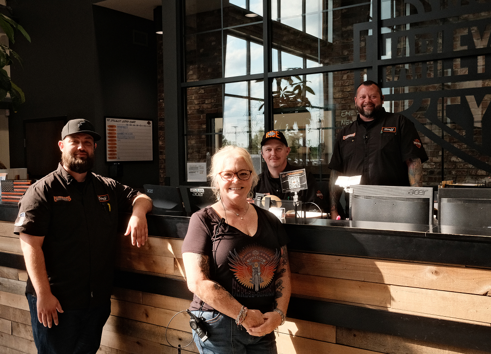 Dealership staff gathered at a wood-paneled service counter inside Bluegrass Harley-Davidson