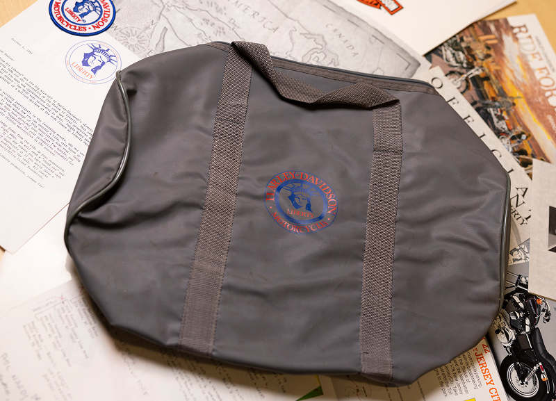 Gray Harley-Davidson Liberty branded bag displayed on top of printed documents and memorabilia