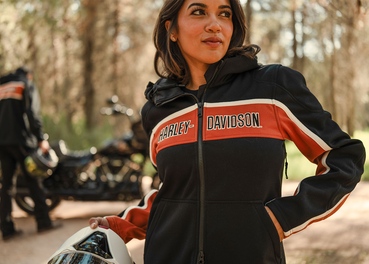 Woman in a black Harley-Davidson zip up jacket with orange and white stripe across front and down sleeves