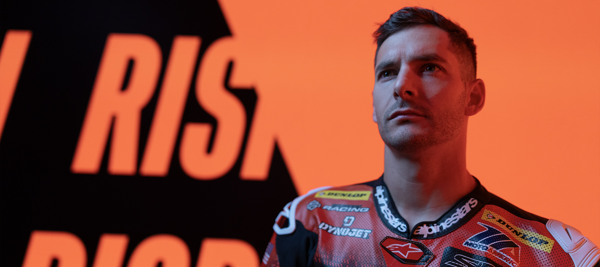 James Rispoli stands in his racing leathers looking up