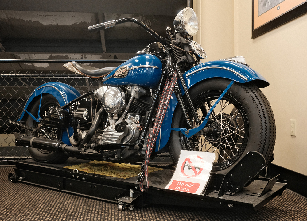 Vintage blue 1946 Harley-Davidson Knucklehead motorcycle displayed indoors with a protective barrier