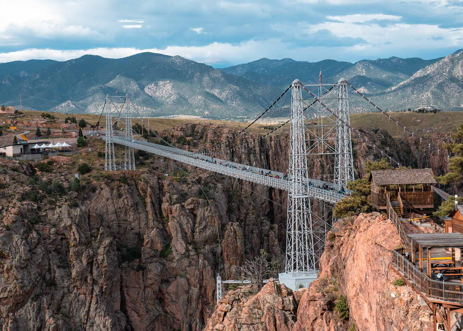 A wide shot of the Royal Gorge suspension bridge, showing the deep canyon below and mountains in the background.
