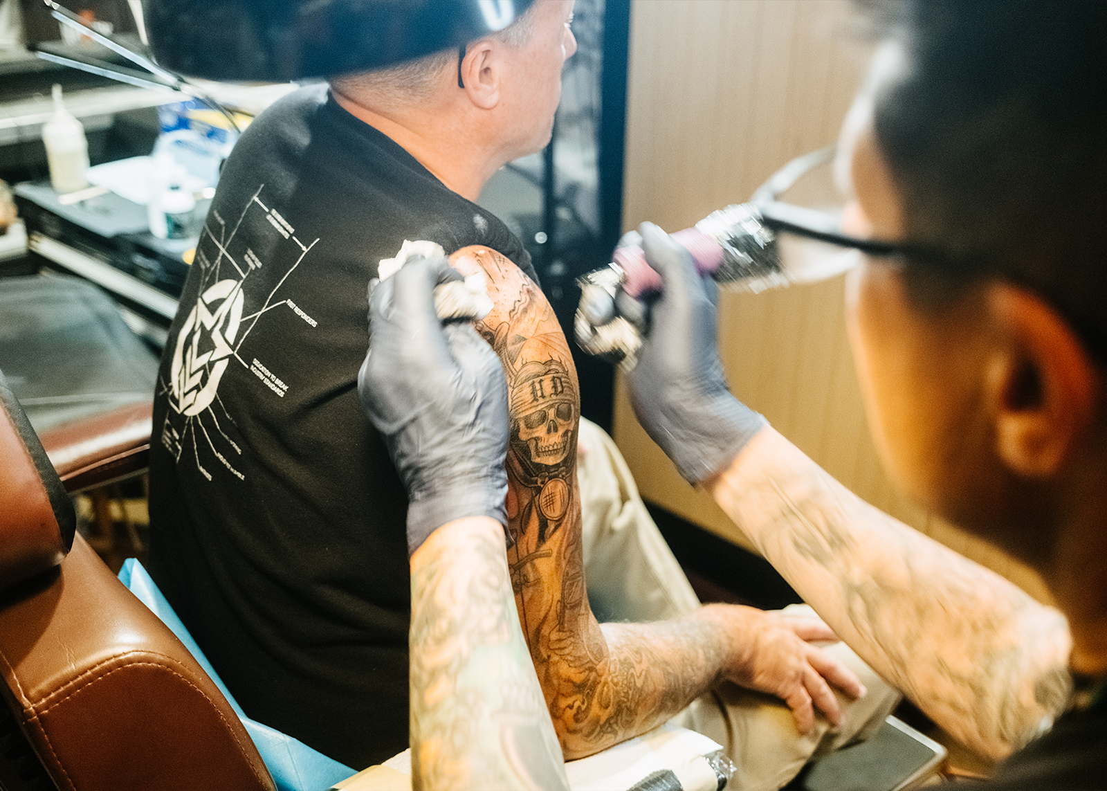 Tattoo artist works on a detailed skull design with H-D initials on a client’s upper arm at the Exit 55 Black Hills rally.