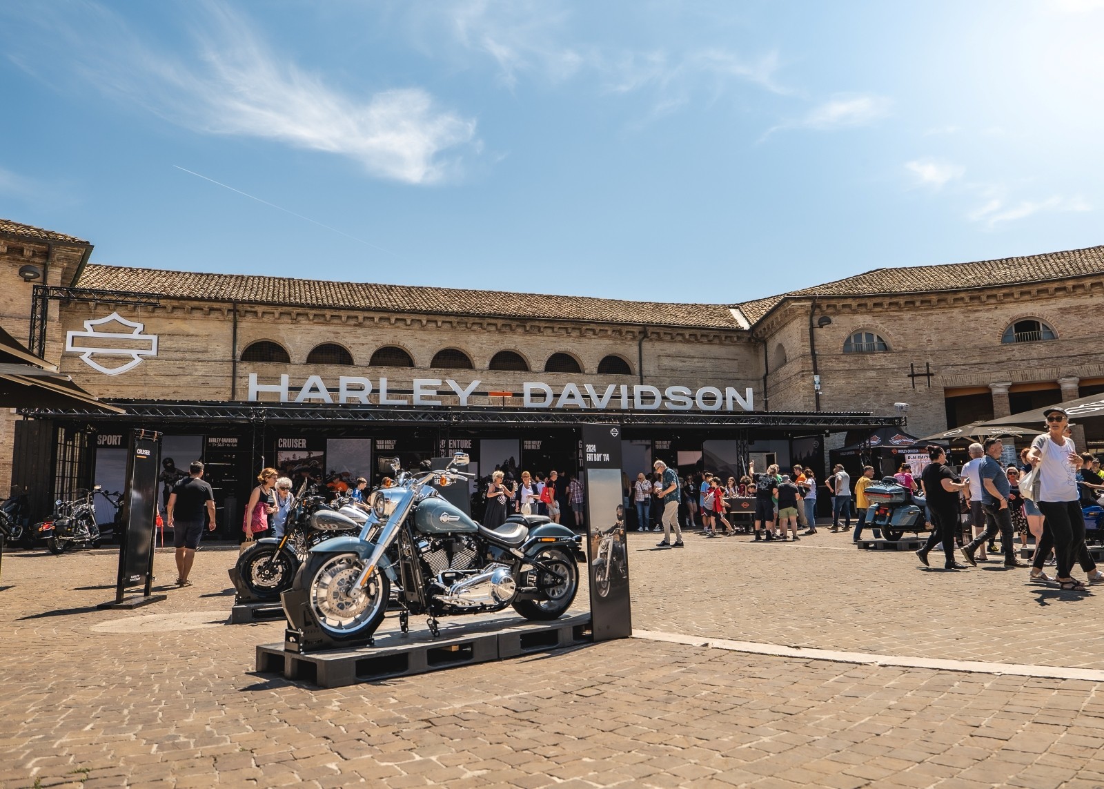 Harley-Davidson motorcycles displayed outdoors with visitors gathered around
