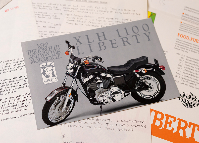 Vintage postcard featuring the 1986 XLH 1100 Liberty model resting on Liberty-themed printed ephemera