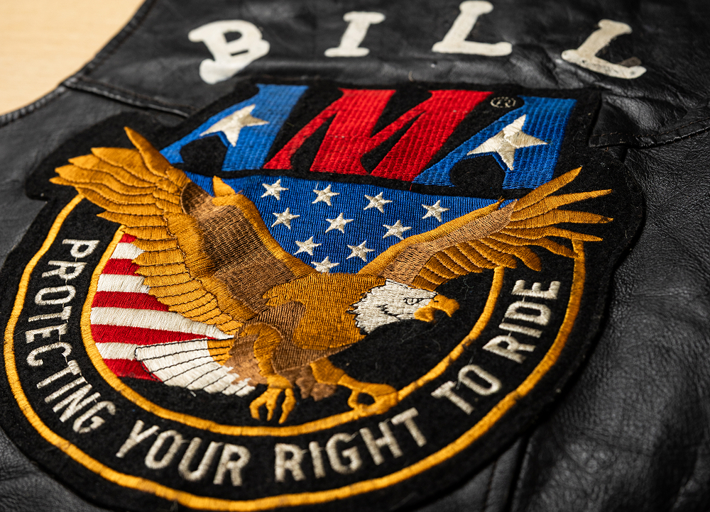Close-up of a black leather vest with a back patch showing an eagle, U.S. flag shield, and embroidered text and symbols