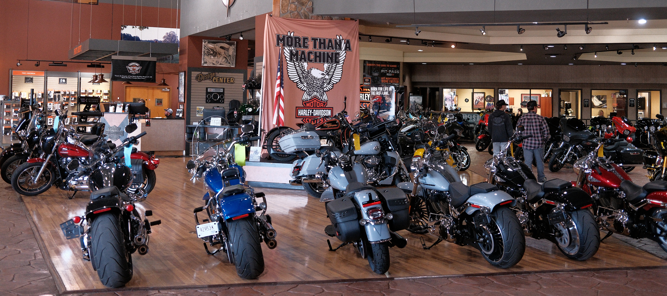 Wide view of Bumpus Harley-Davidson showroom with rows of motorcycles, wood floors, banners, and parts counters