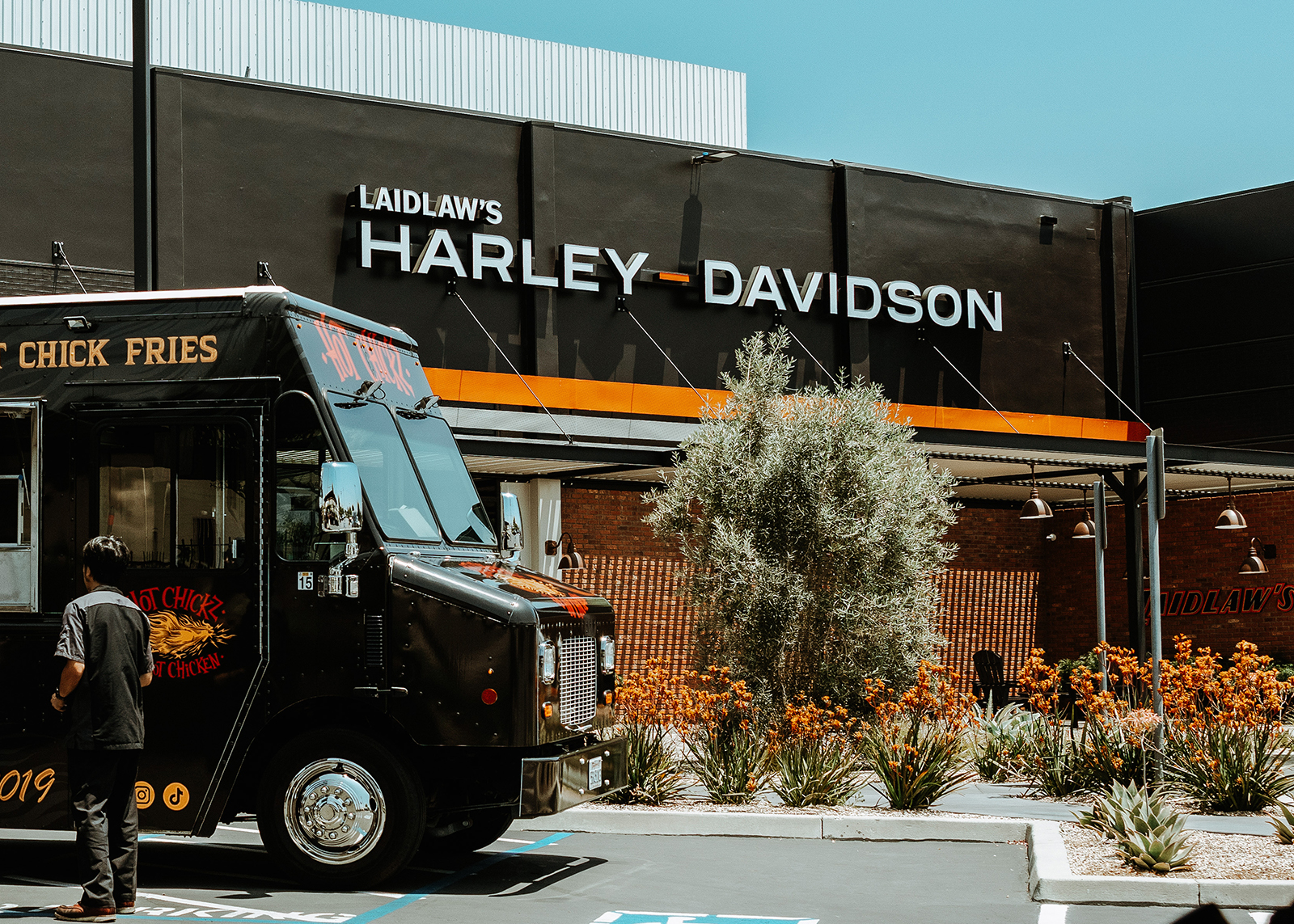 People order from a food cart that is parked in front of the Laidlaw’s Harley-Davidson dealership.