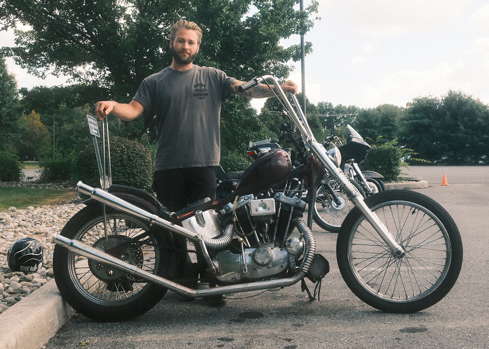 A young staff member at Classic Harley-Davidson stands behind his custom built Ironhead chopper in the parking lot at Classic Harley-Davidson.