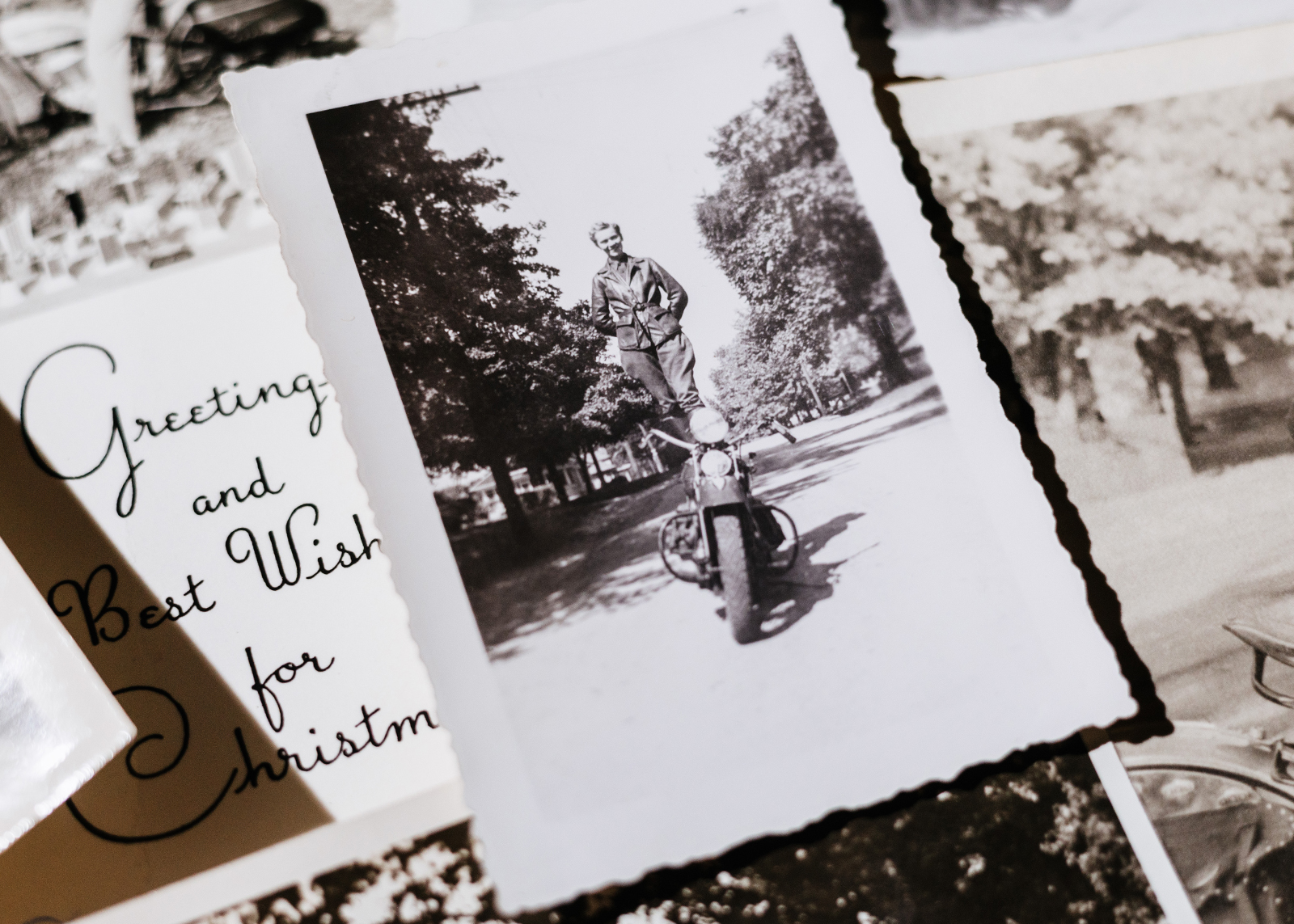 A photo of a vintage Motor Maid photo showing a woman standing on the seat of her motorcycle, surrounded by other vintage photos.