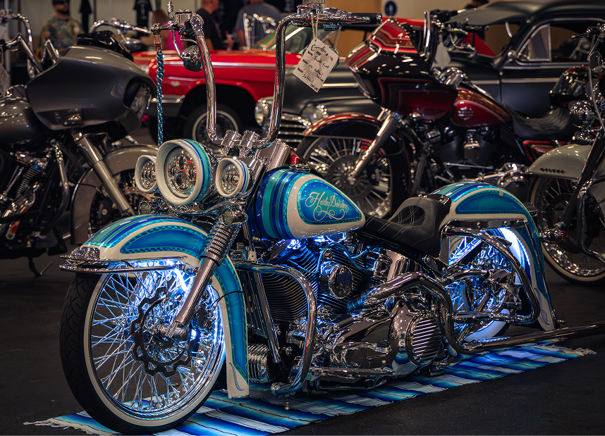 Blue Vicla style motorcycle with detailed chrome work displayed on a mat among other show bikes