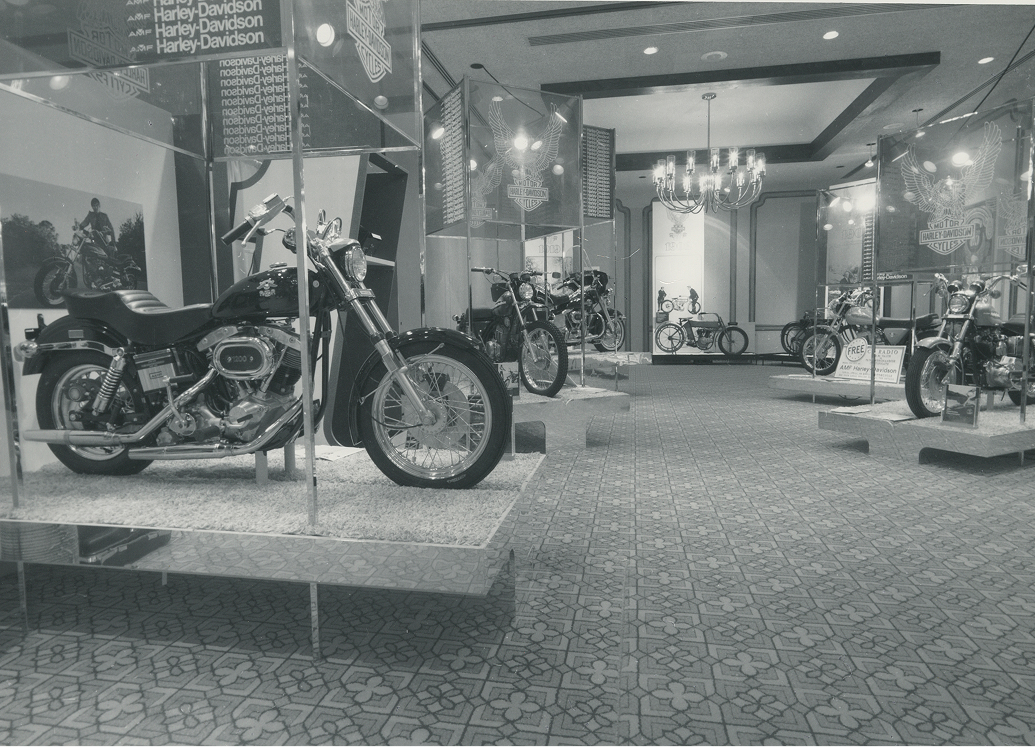 The “A Salute to American Motorcycling” exhibition with multiple motorcycles displayed in a showroom with overhead signs