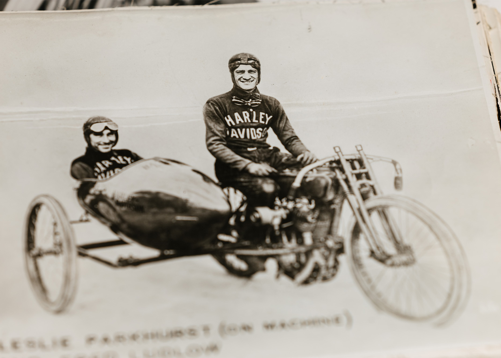 Red sits on a Harley with another man in his sidecar.