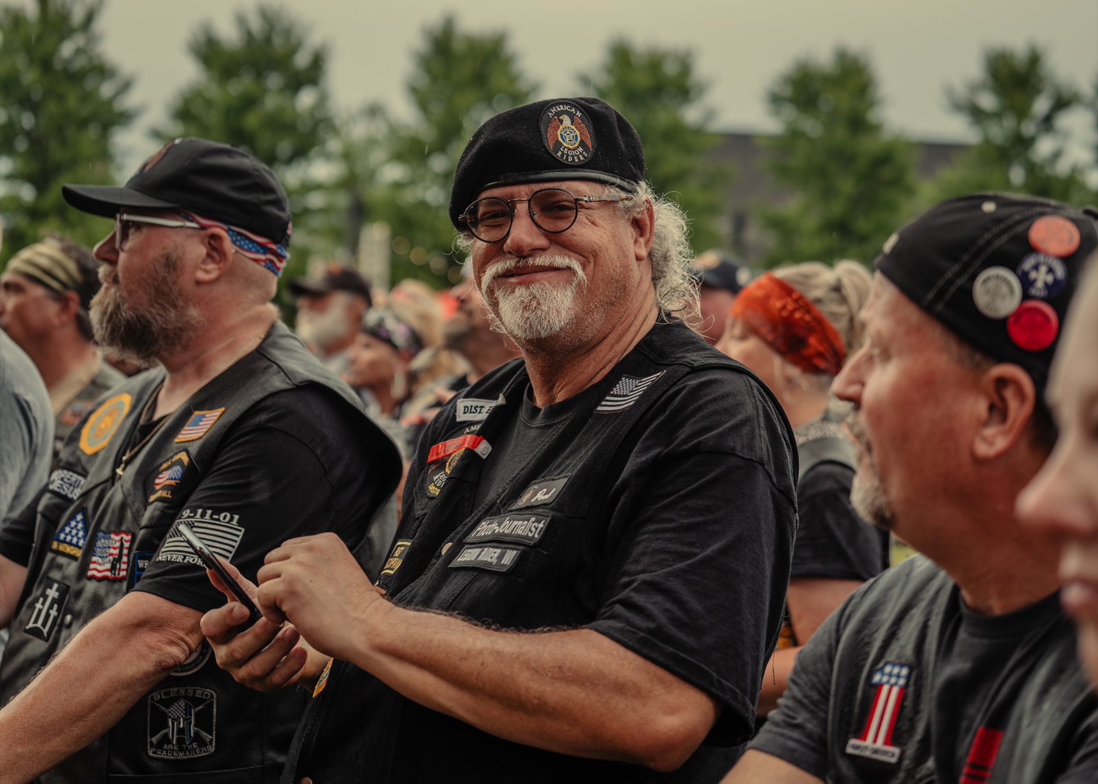 A smiling Veteran with a grey beard standing with his friends
