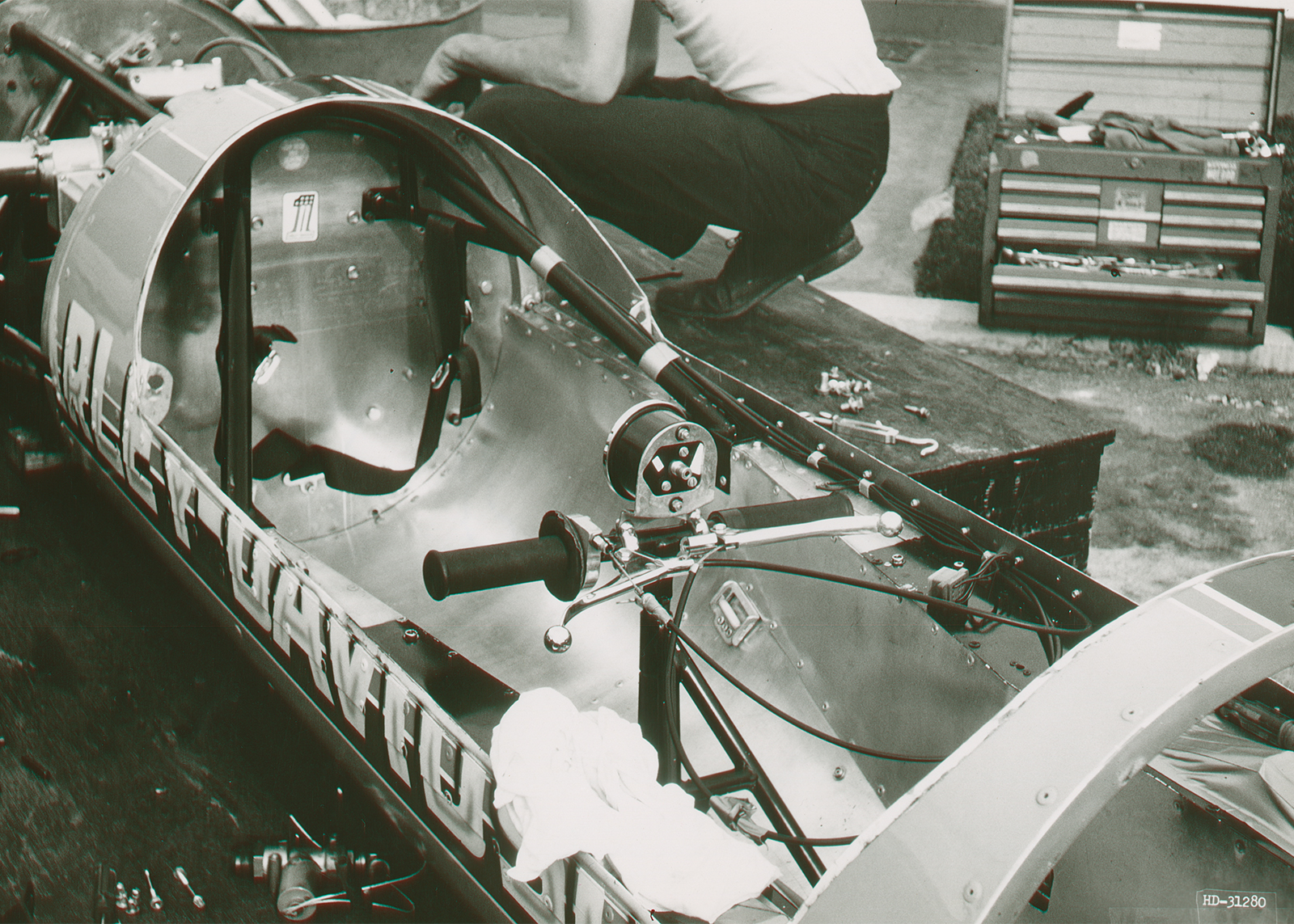 A shot inside the Sportster streamliner in a garage, showing the almost empty metal inside with the handlebars, seatbelt, and a few other gadgets.