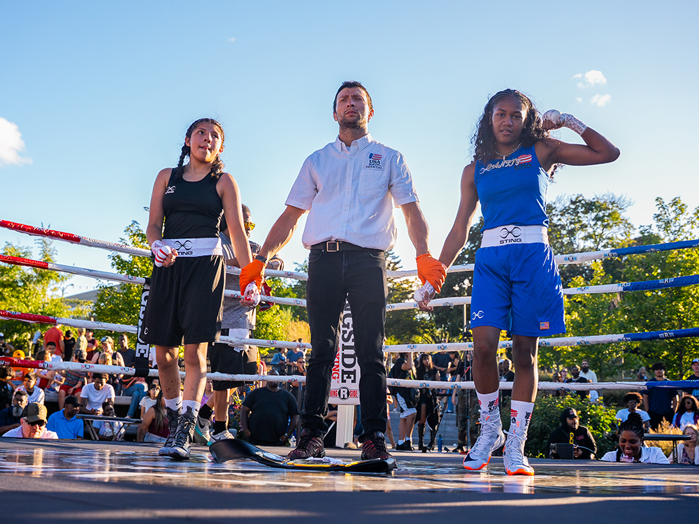 Young boxing champions standing with referee in outdoor ring