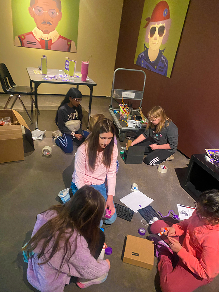 Children sitting on floor doing crafts in indoor activity space