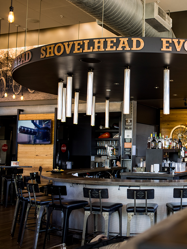 Circular bar area with stools and overhead sign reading Shovelhead Evo inside venue