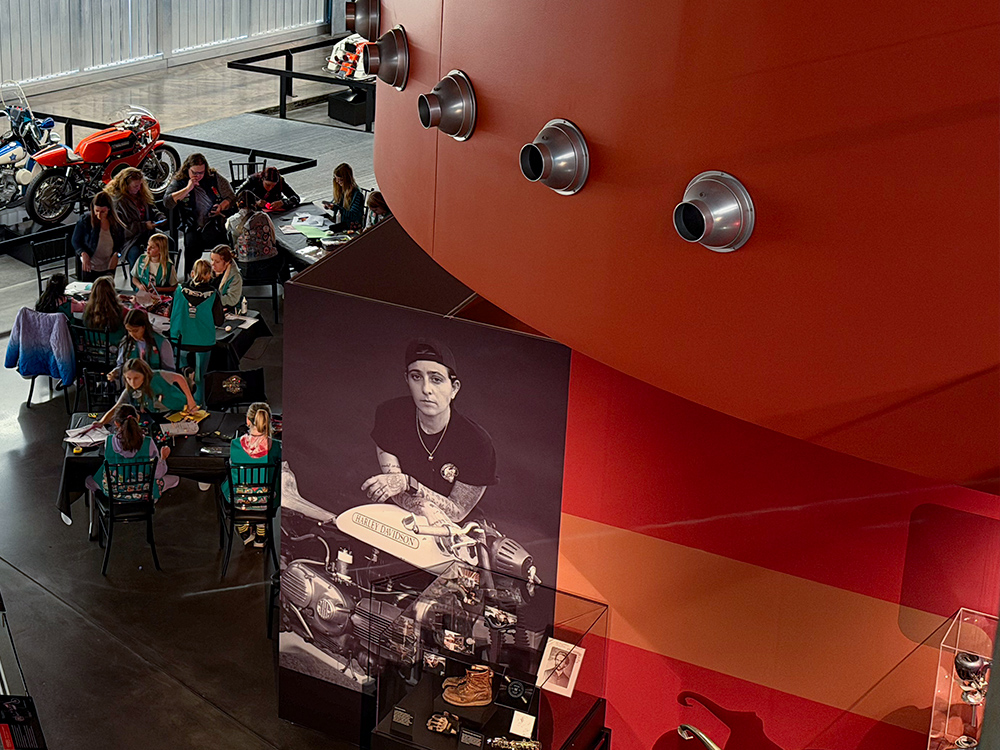 Visitors exploring Harley-Davidson museum exhibit with historic displays