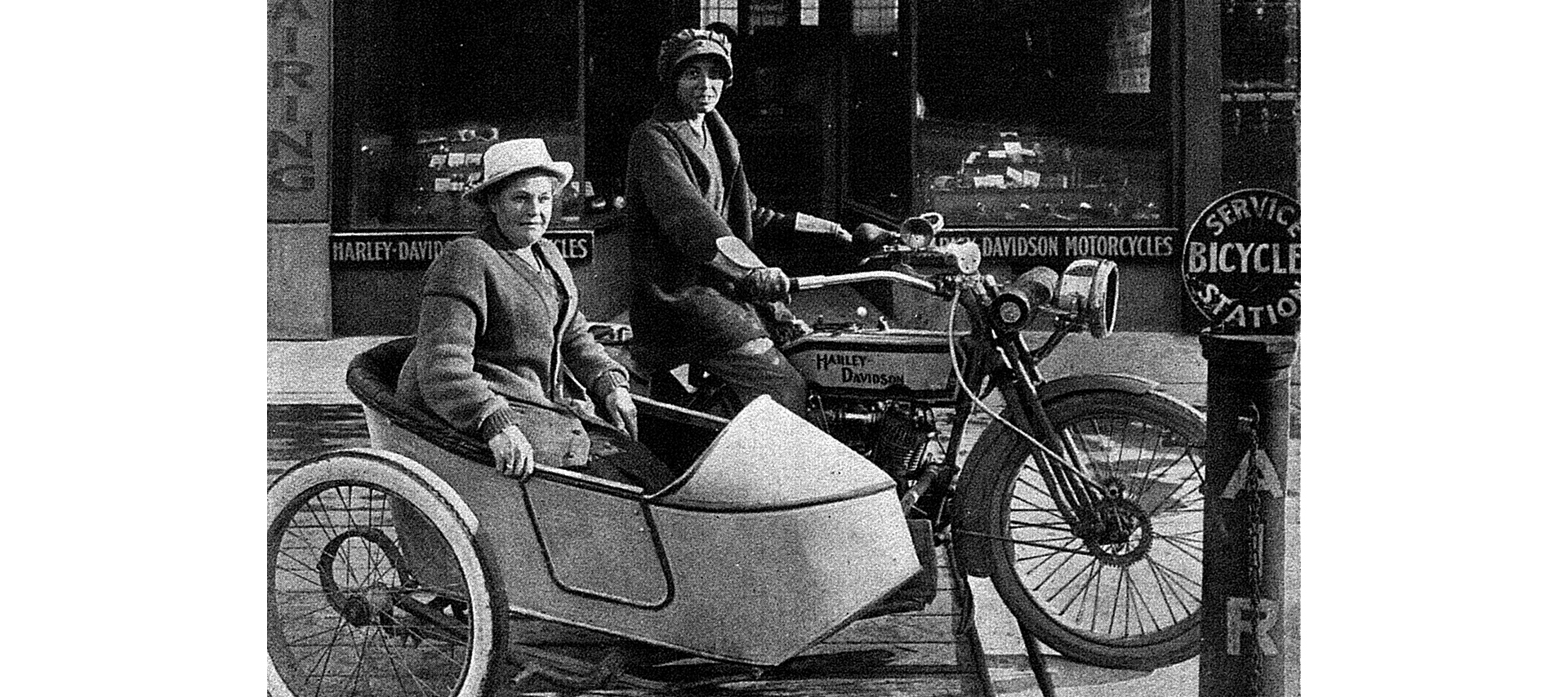 One woman rides a motorcycle with another woman in the attached sidecar 