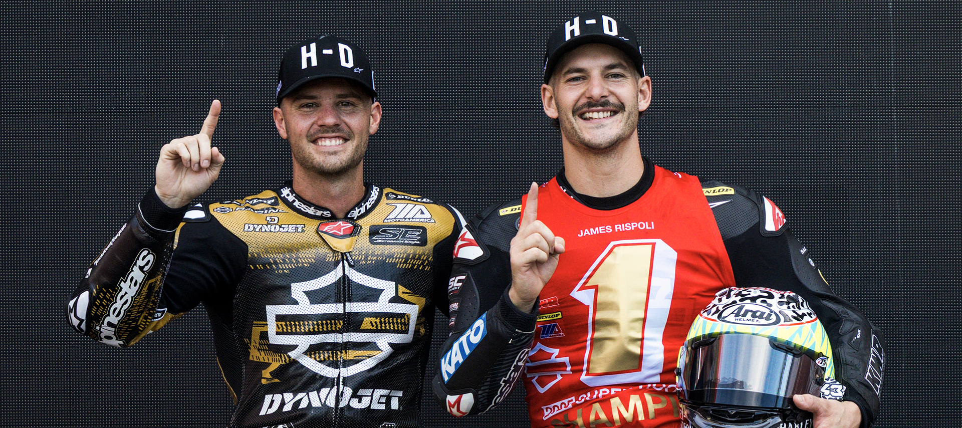Smiling Kyle Wyman and James Rispoli sit side-by-side showing number one with their index finger at the end of the King of the Baggers season.