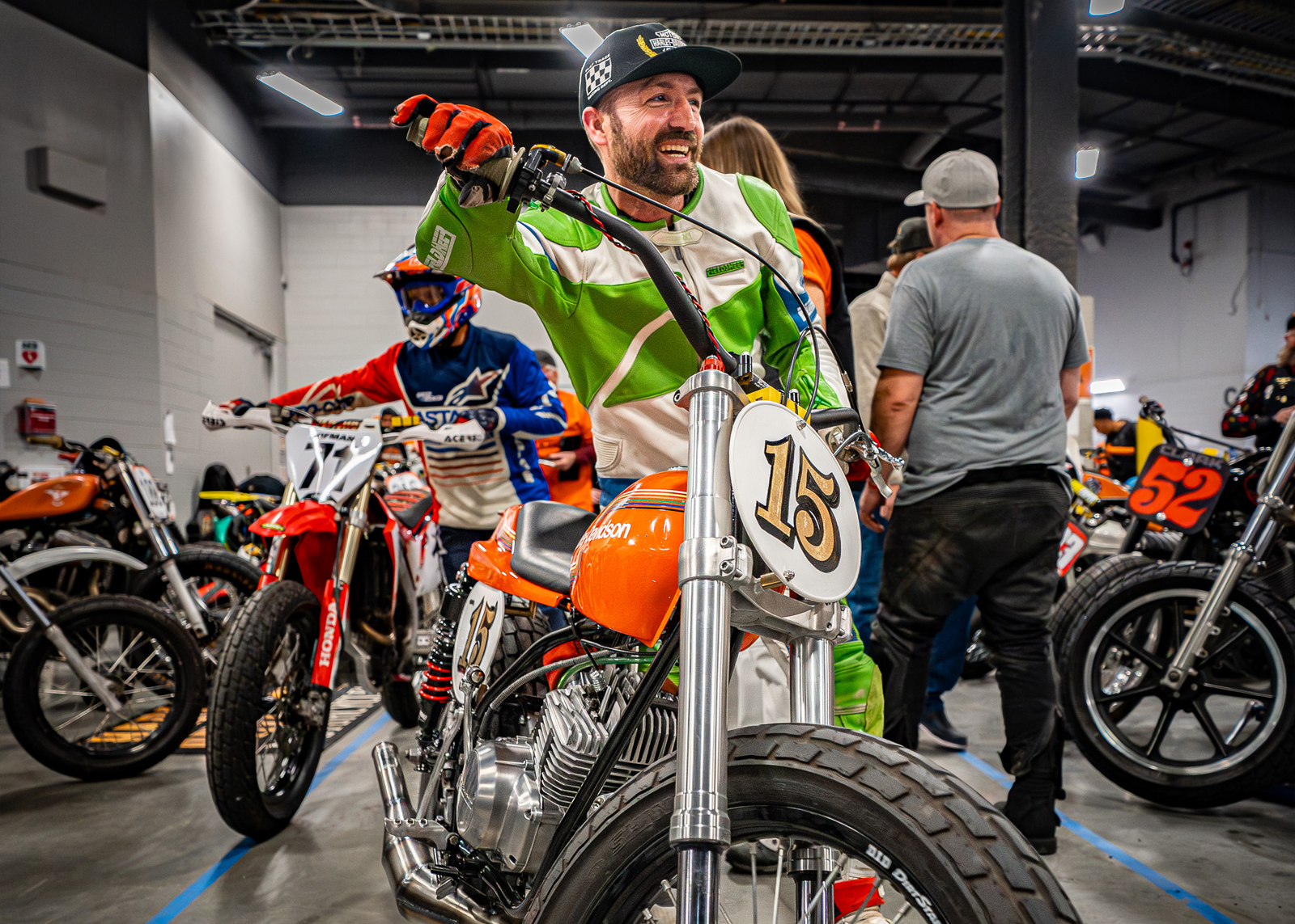 A man smiles wheeling his number 15 race bike out of the pits