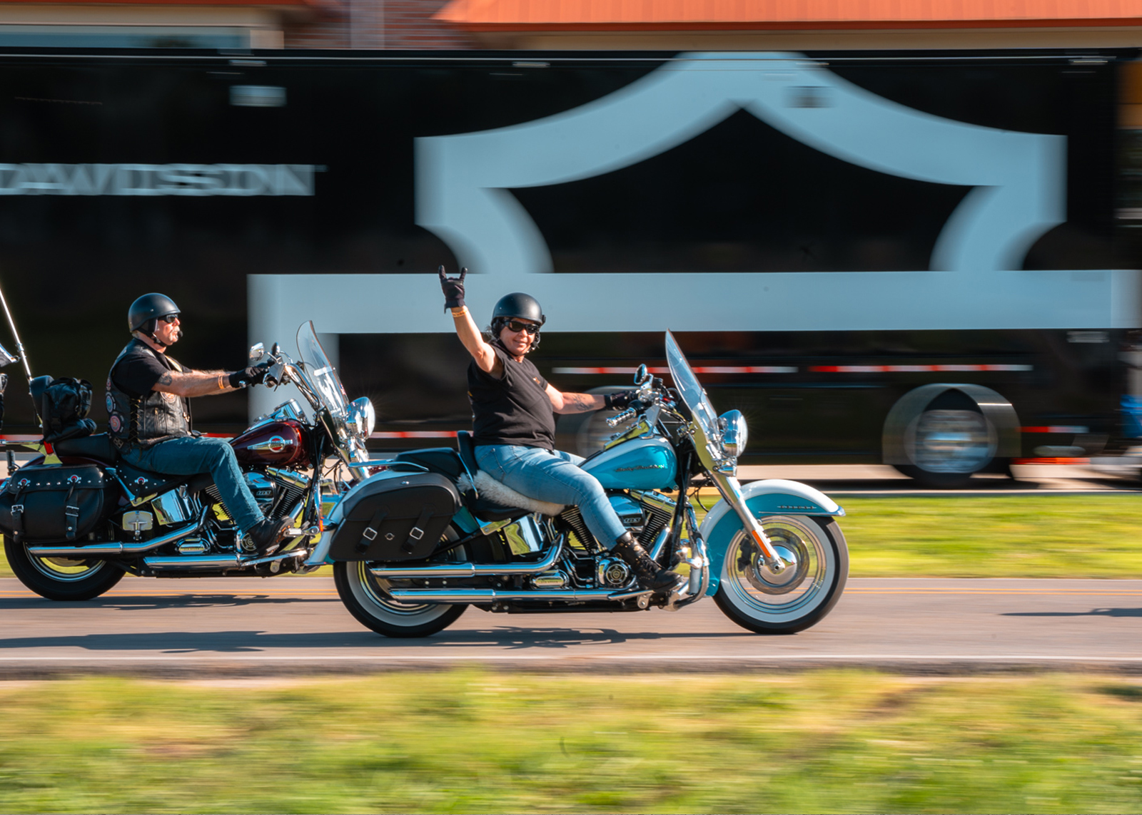 A woman riding a motorcycle holds up the "rock on" hand sign
