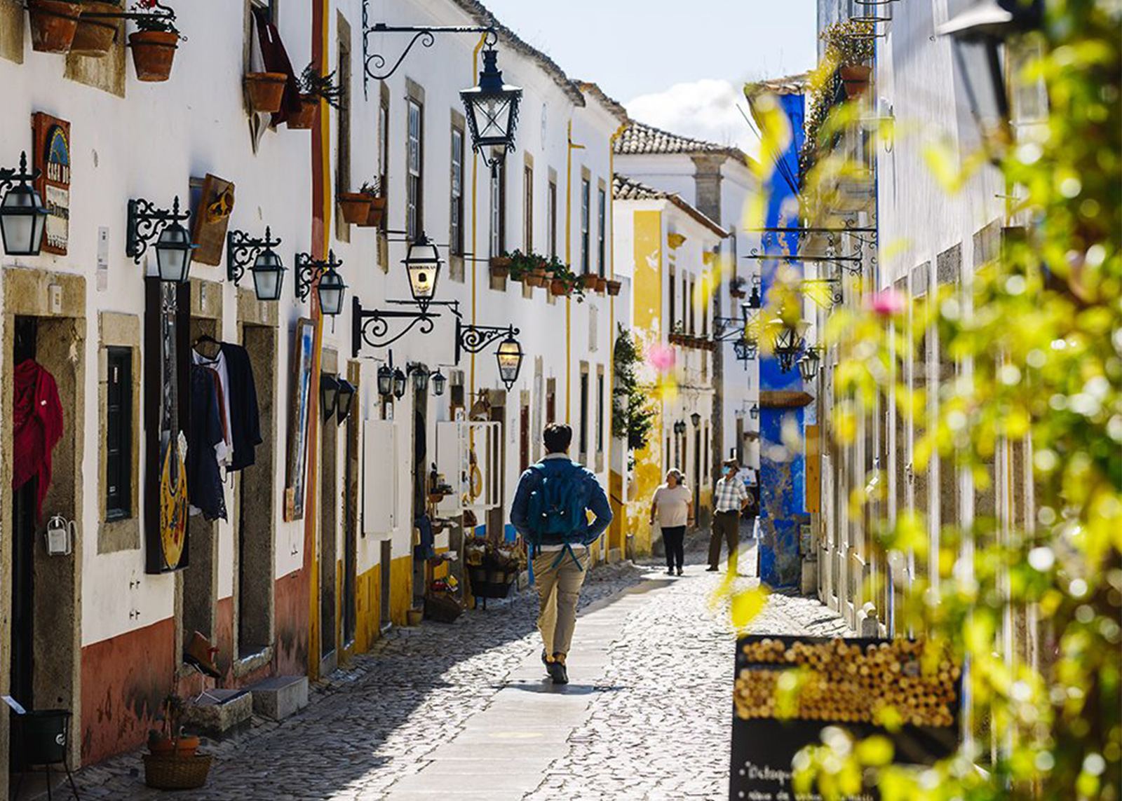 Man walks on cobblestone street linked with whitewashed buildings in Obidos
