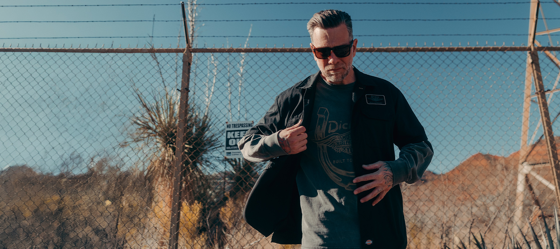 man wearing dickies shirt in front of fence