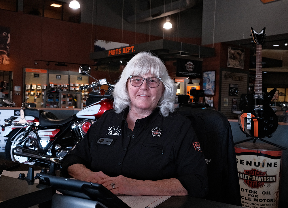 Bumpus Harley-Davidson dealership staff member at a counter inside the showroom, with motorcycles and parts displays behind