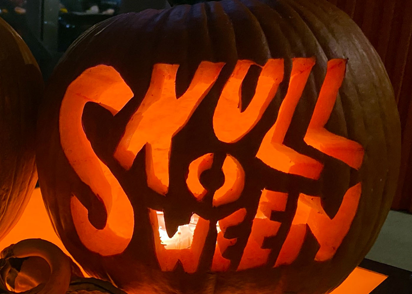 Carved Halloween pumpkin displaying “Skulloween” with illuminated lettering