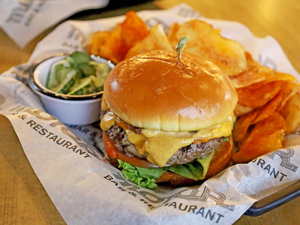 Cheeseburger with melted cheese served with chips and pickles