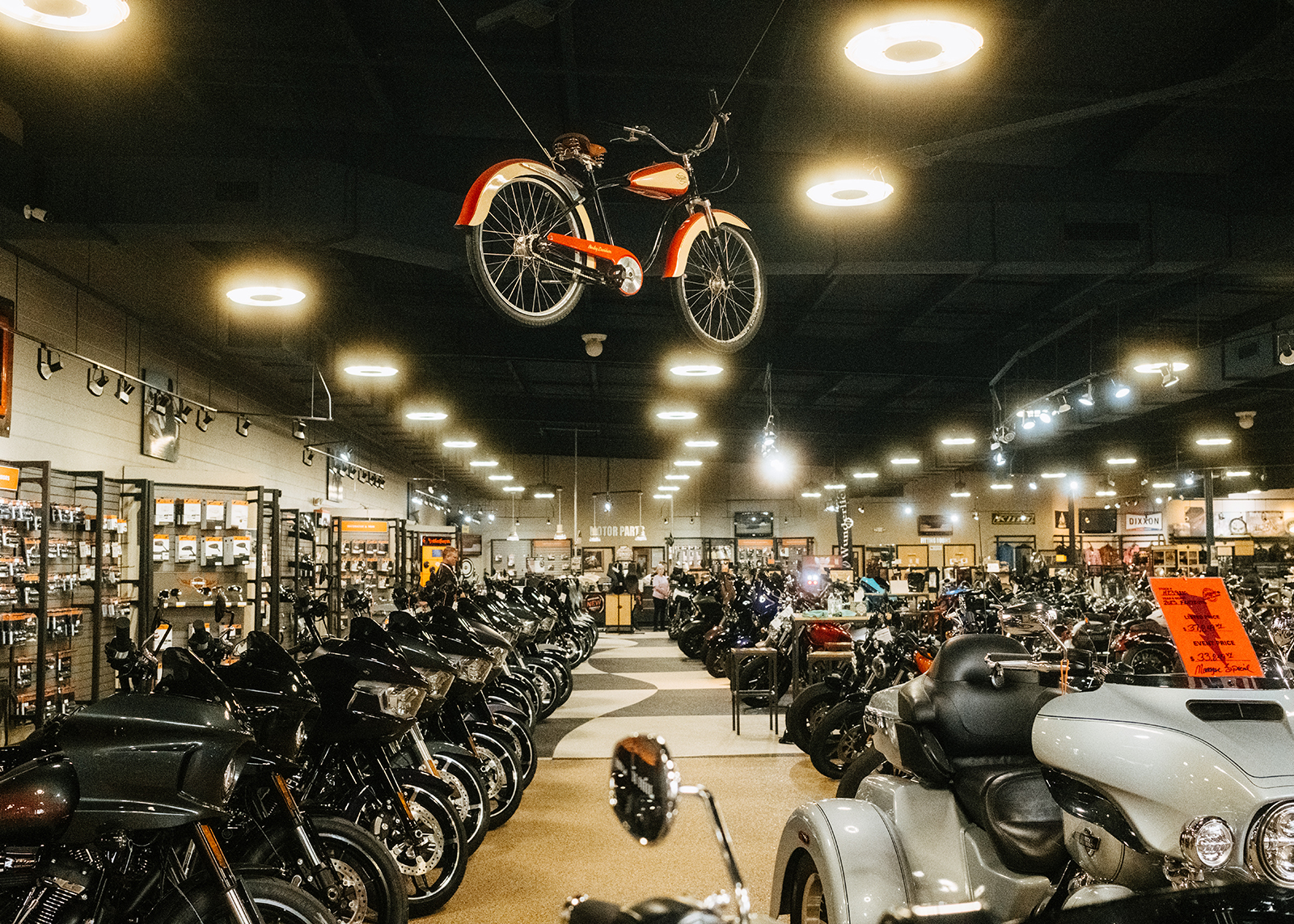 A wide shot of the showroom floor at White Lightning Harley-Davidson with a vintage red and white bicycle hanging from the ceiling.