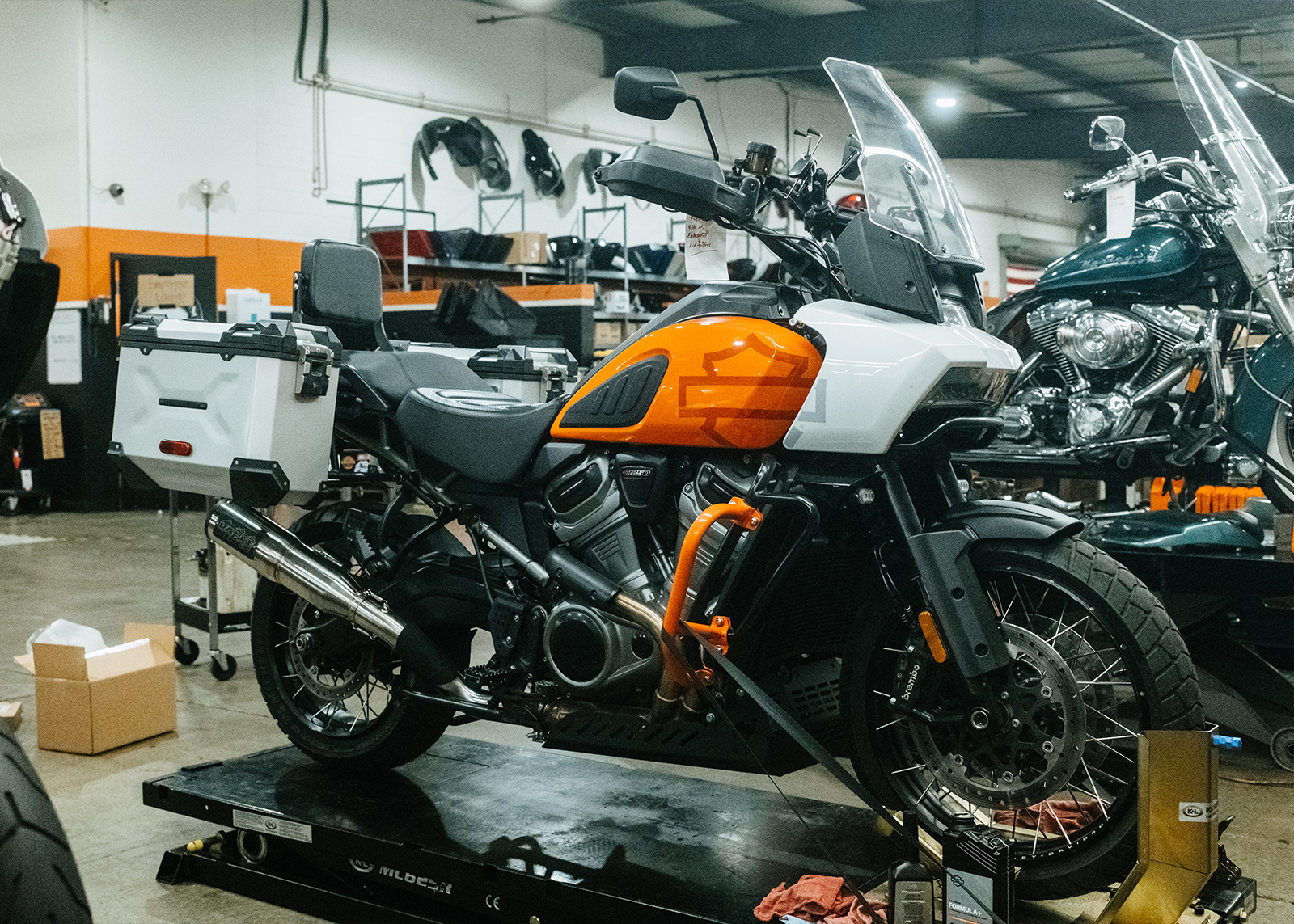 An orange and white H-D Pan America sits on a lift in the service area of White Lightning Harley-Davidson.