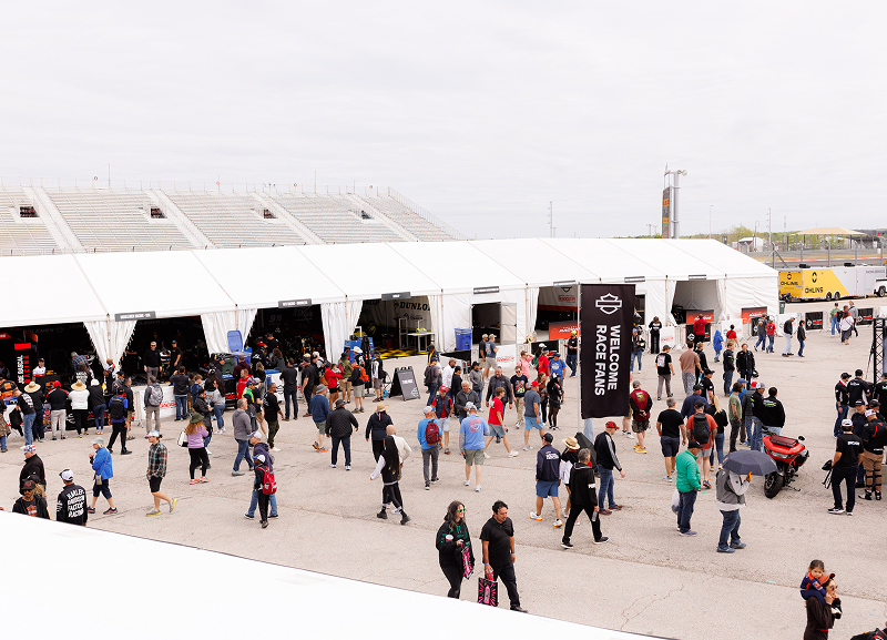 Crowds gather outside the Harley-Davidson fan zone and paddock area during a motorcycle race event