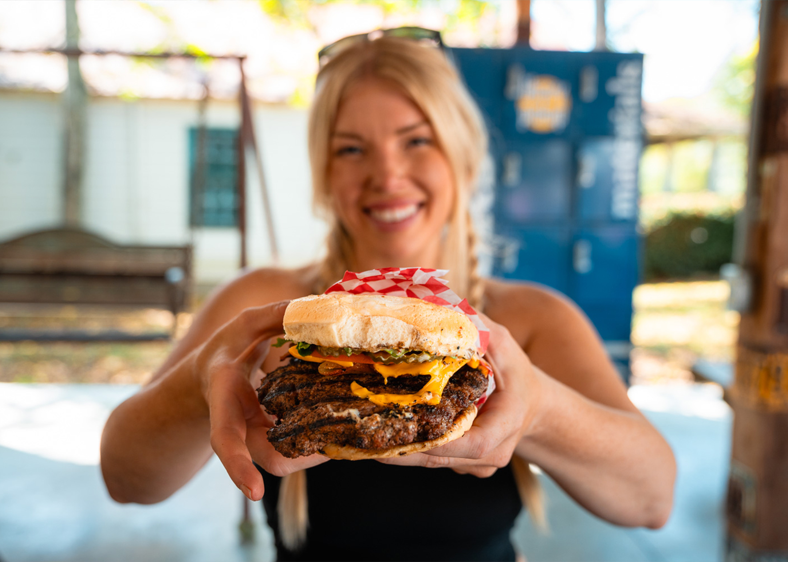 A woman smiles holding a burger 