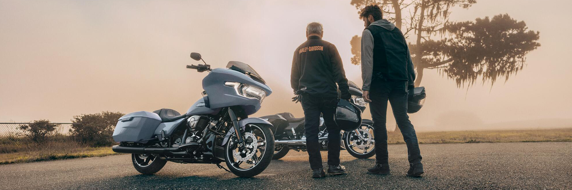 Motorcyclists stand next to bikes on side of road