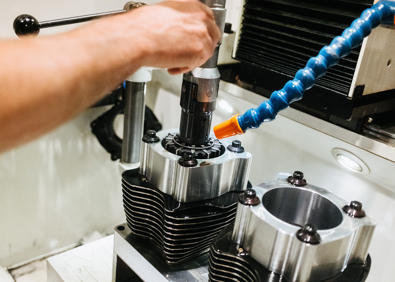 Close-up view of a machinist’s hand honing a Harley-Davidson engine cylinder head.