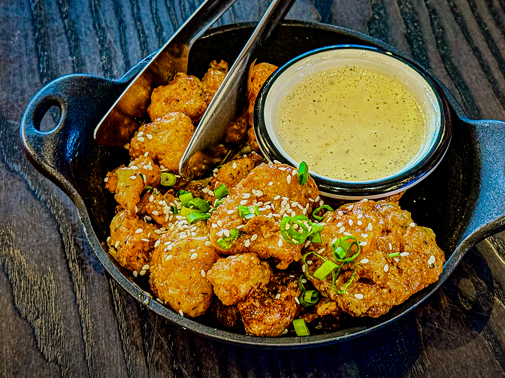 Bowl of crispy fried chicken bites with dipping sauce.