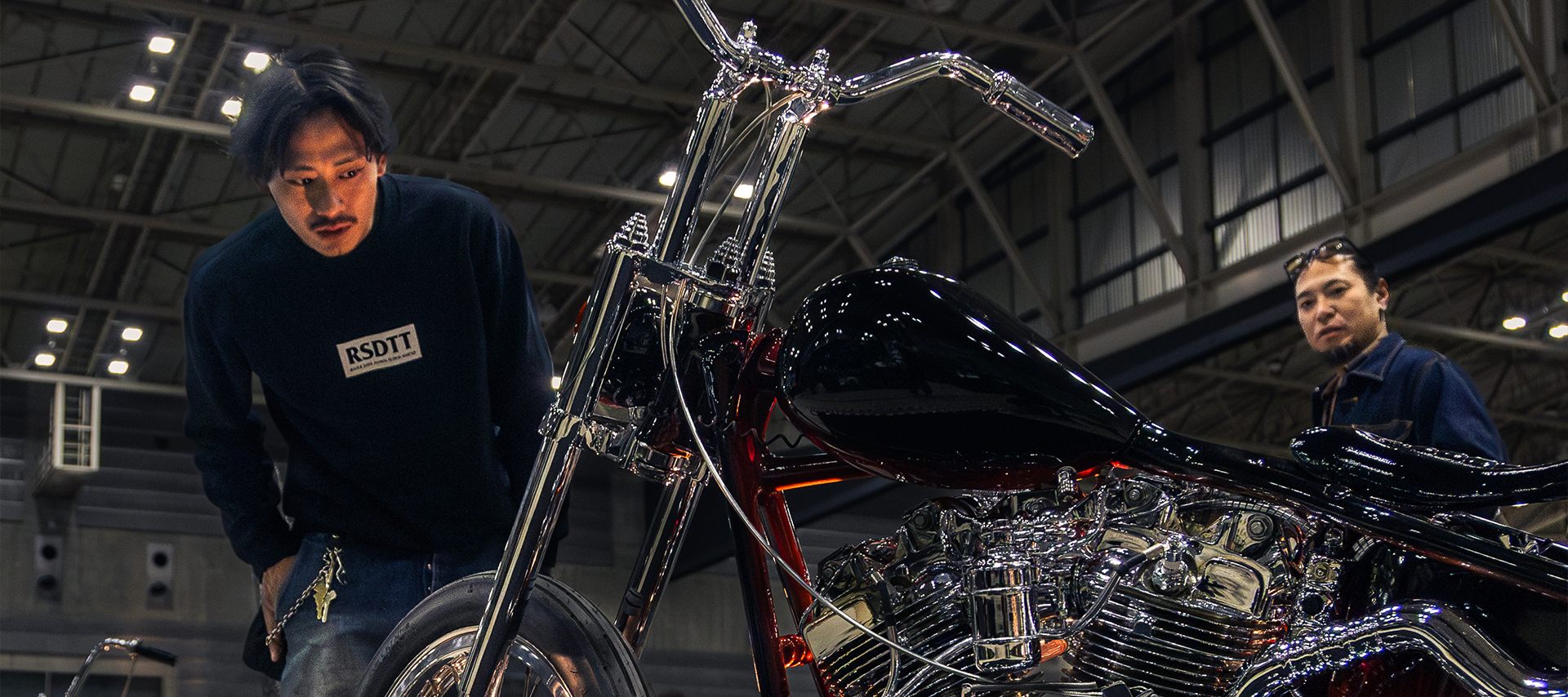 Onlookers check-out a custom Harley-Davidson chopper with chrome detailing and deep ruby paint