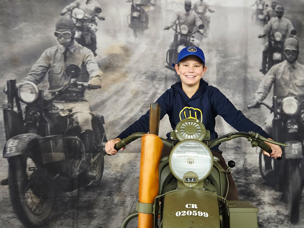 Child posing on vintage military motorcycle in museum display