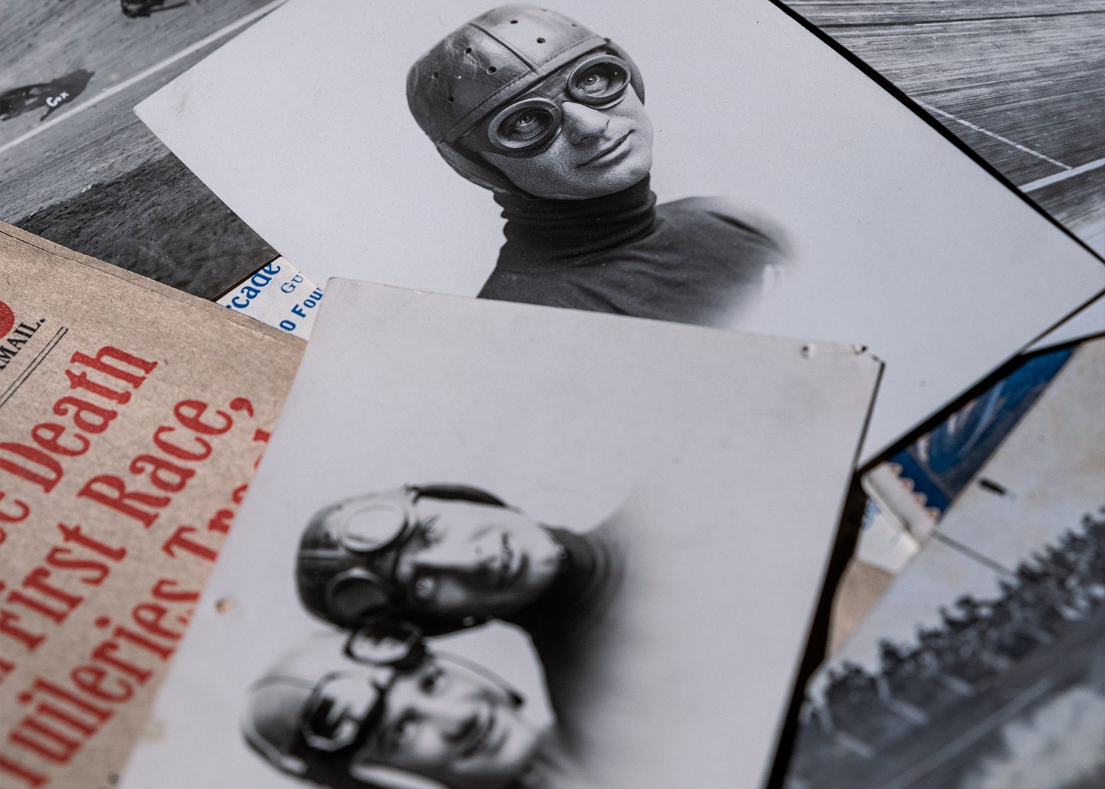 Historic photos of racers and articles from the Bowen collection are scattered on a tabletop